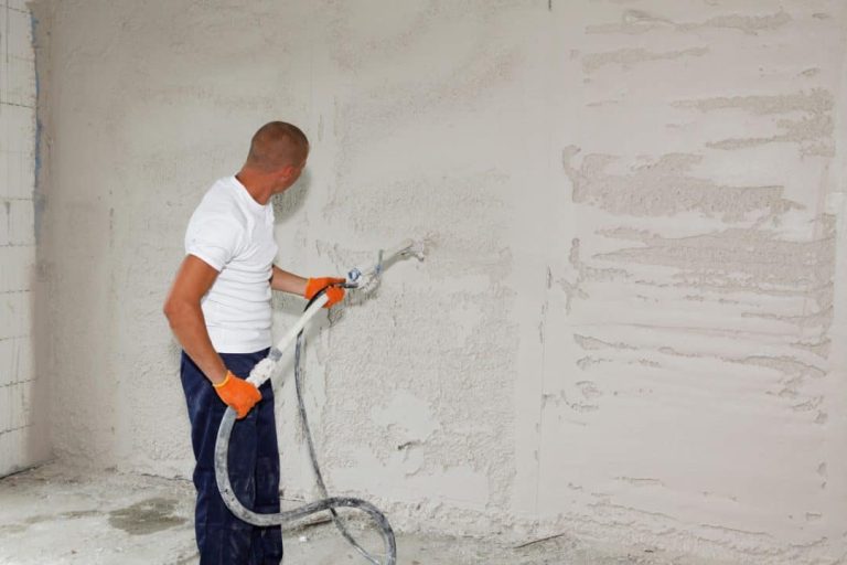 A-man-is-applying-stucco-on-the-wall-plastering-coating-the-wall-by-spraying-stucco-with-a-stucco-sprayer